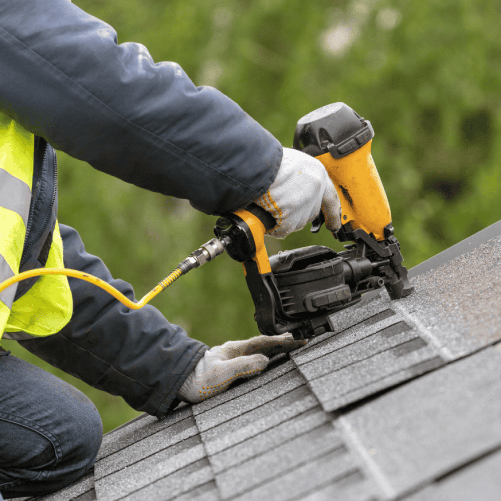 man drilling nails into roof shingles